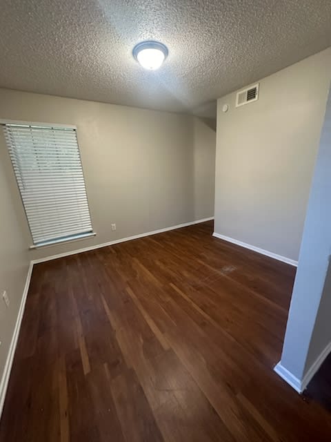 an empty room with wood floors and a window