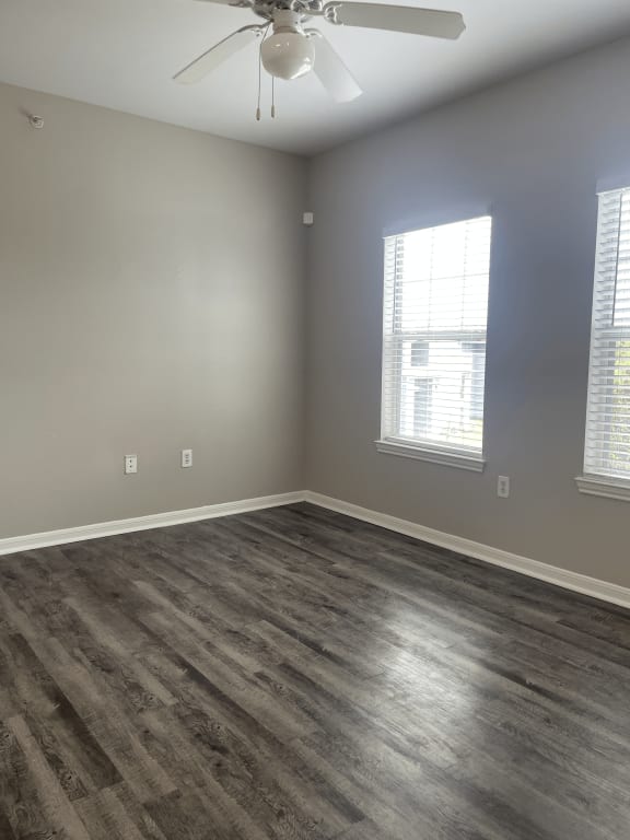 an empty bedroom with wood floors and a ceiling fan