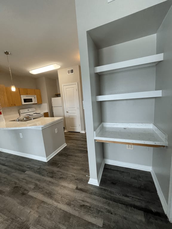 an empty kitchen with white shelves and a counter