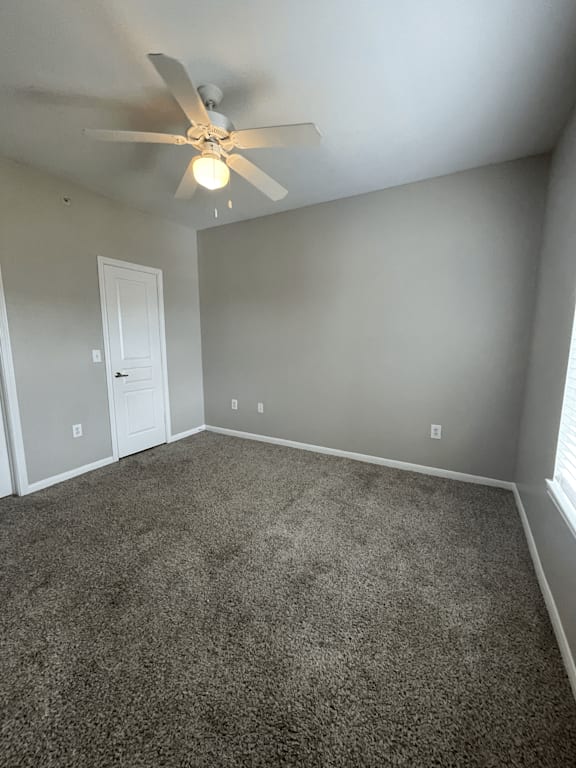 an empty room with carpet and a ceiling fan