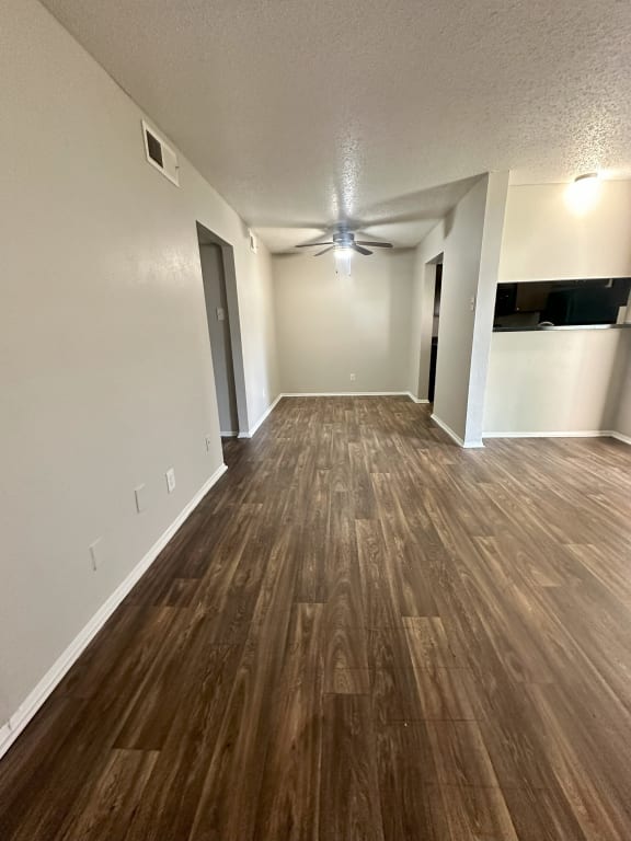 an empty living room with wood flooring and a ceiling fan