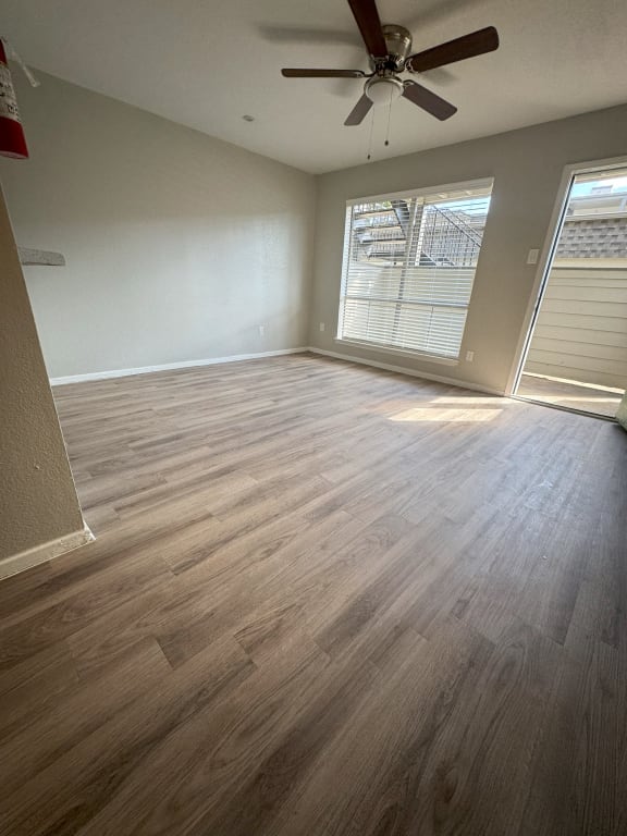 an empty living room with wood floors and a ceiling fan