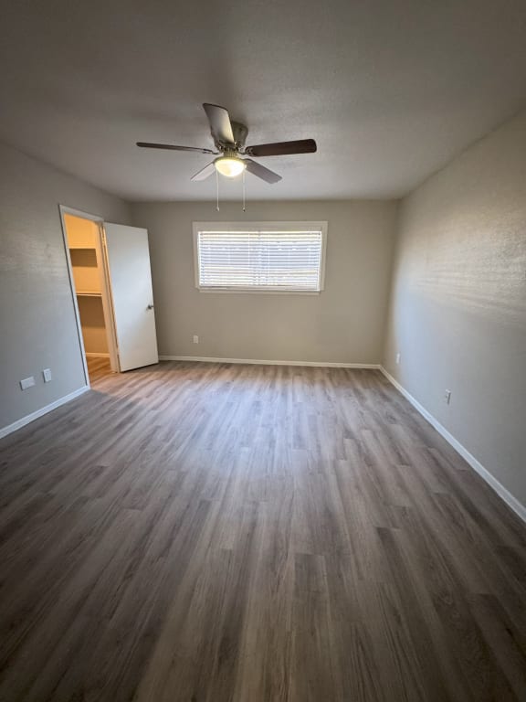 an empty living room with wood floors and a ceiling fan