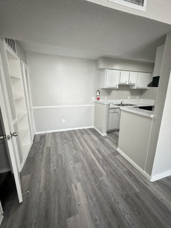 an empty kitchen with wooden floors and white cabinets