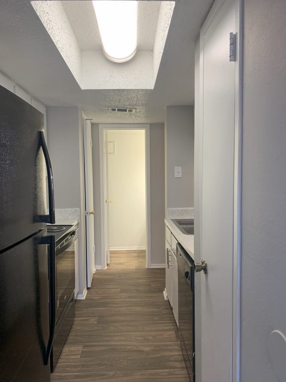 a kitchen with stainless steel appliances and a long hallway with a door to a closet  at 1505 Exchange Apartments, Texas, 76112