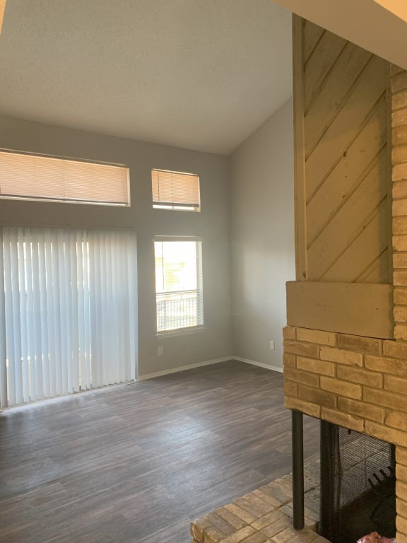 an empty living room with a brick fireplace and wood floors  at 1505 Exchange Apartments, Fort Worth, TX
