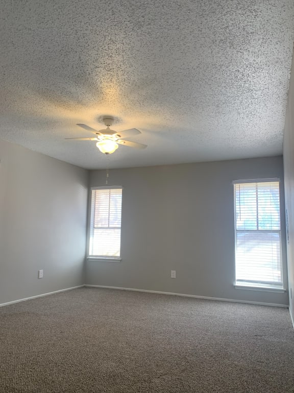 an empty living room with a ceiling fan and two windows  at 1505 Exchange Apartments, Fort Worth, TX, 76112