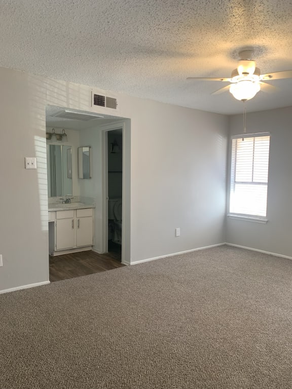 an empty living room with a ceiling fan and a bathroom  at 1505 Exchange Apartments, Fort Worth, TX