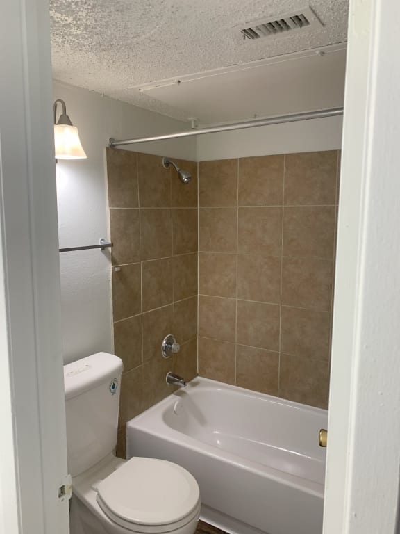 a bathroom with a toilet and a tub and a sink  at 1505 Exchange Apartments, Fort Worth, Texas