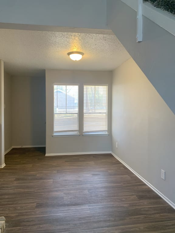 an empty living room with wood floors and two windows  at 1505 Exchange Apartments, Fort Worth, 76112
