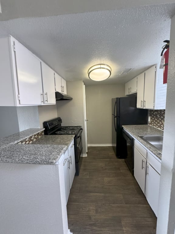 a kitchen with white cabinets and a black refrigerator