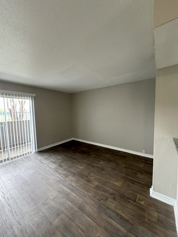 an empty living room with wood flooring and a window