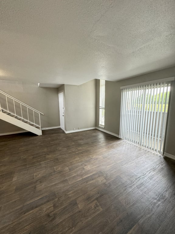 an empty living room with wood flooring and a staircase