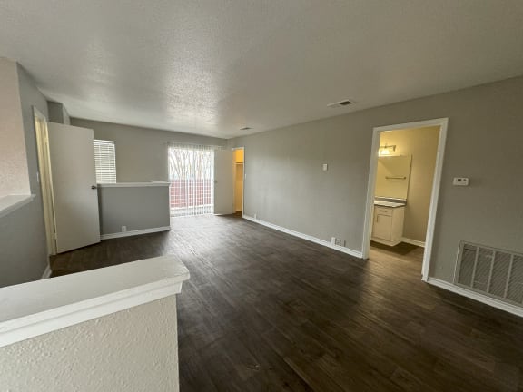 an empty living room with wood flooring and a window