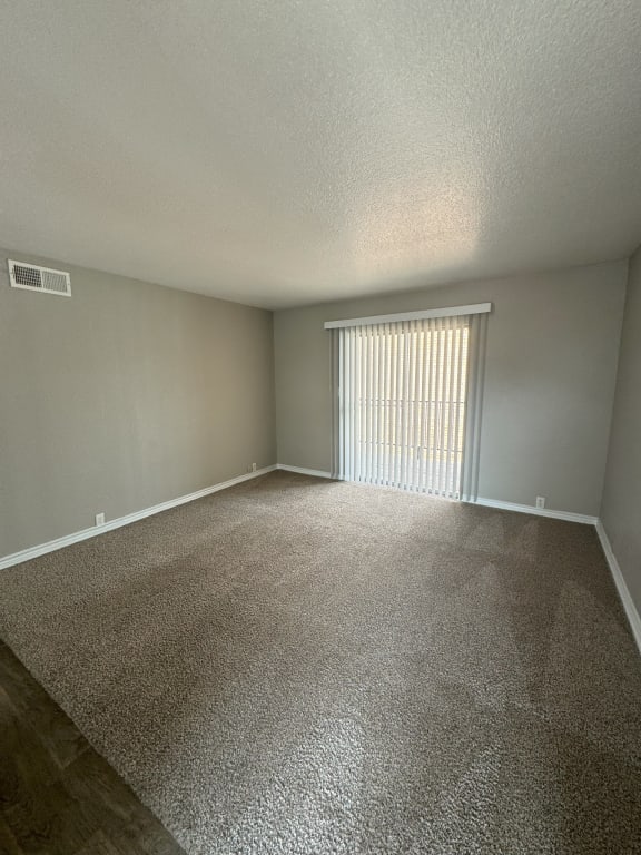 an empty living room with a window and carpet