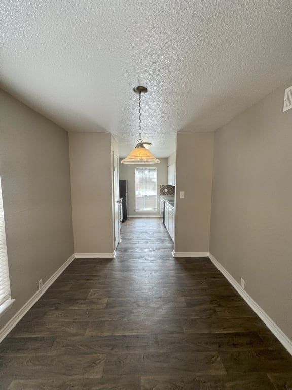 an empty living room and hallway with wood flooring and a chandelier