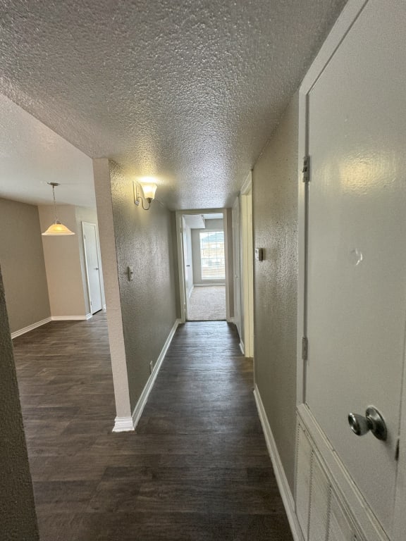 a hallway with a wood floor and white walls and a door