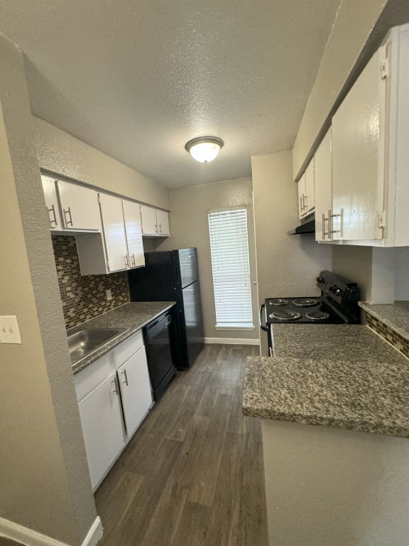 a kitchen with granite counter tops and white cabinets