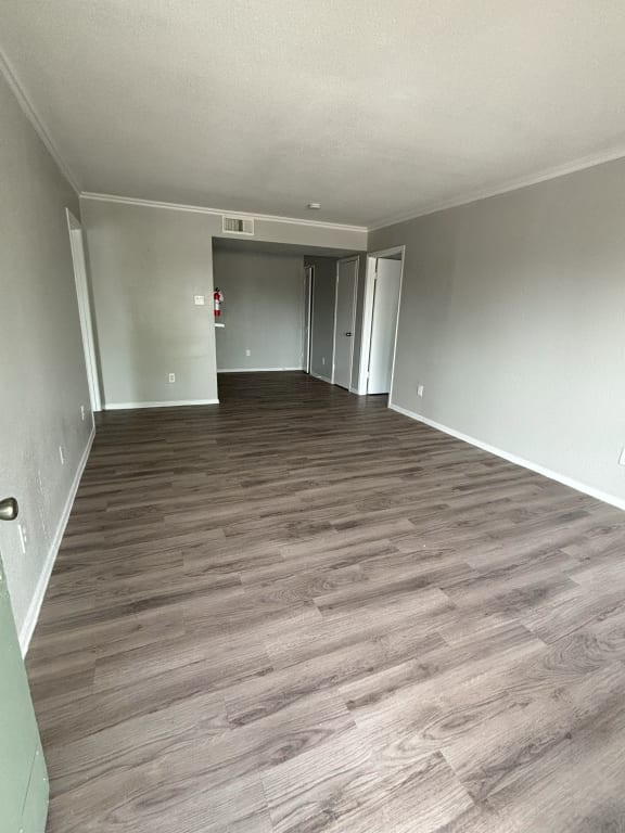 an empty living room with wood flooring and white walls