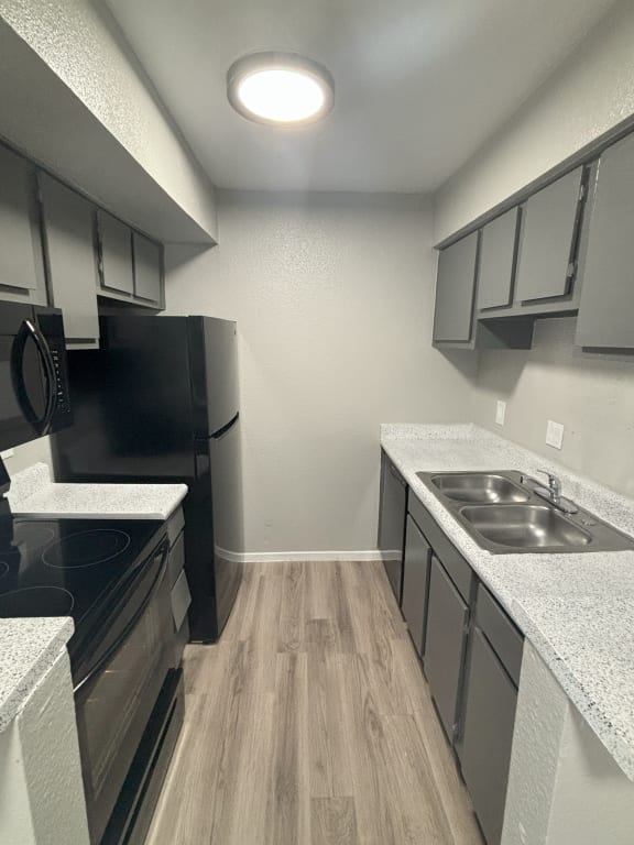 an empty kitchen with stainless steel appliances and white countertops