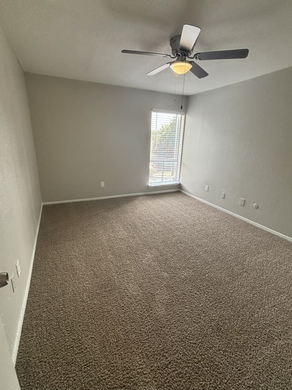 an empty room with a ceiling fan and a window