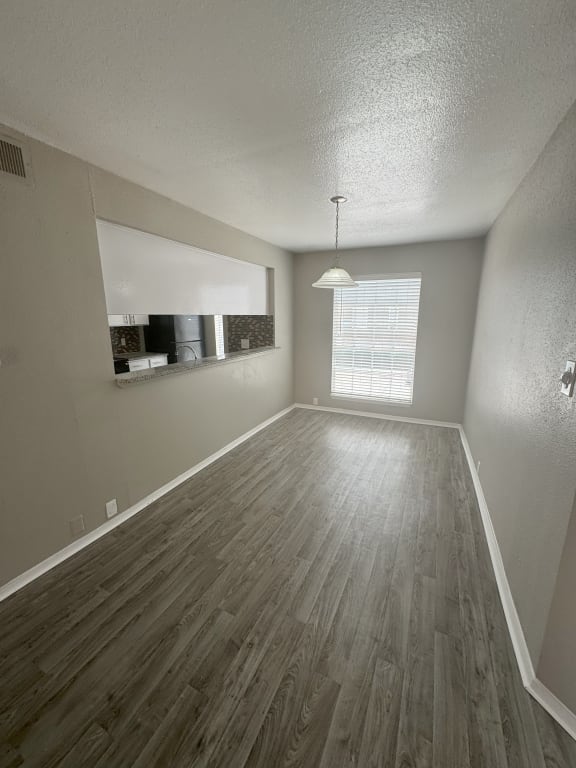 an empty living room with wood flooring and a window