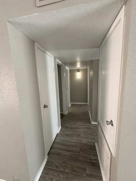 a hallway with white walls and wood flooring and a white door