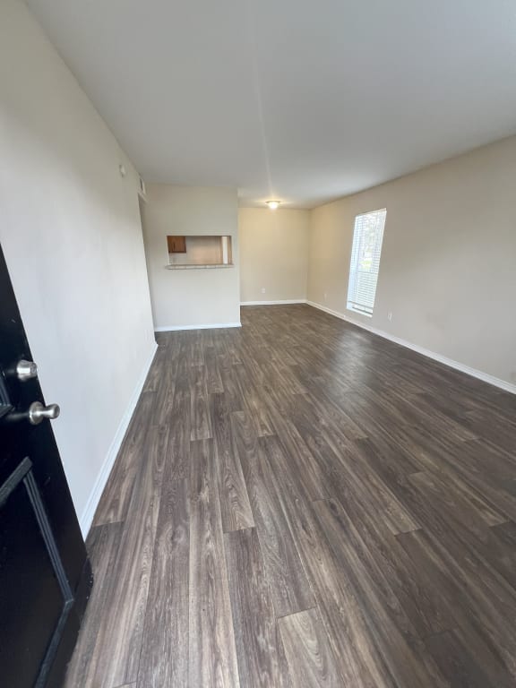 an empty living room with wood floors and white walls