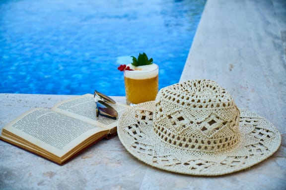a book and a hat next to a pool  at Oaks of Westchase, Houston