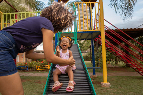 a mother plays with her child on a slide  at Cambridge Village, Texas