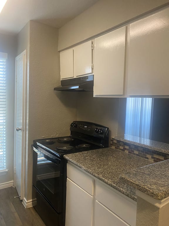 a kitchen with white cabinets and a black stove &#xA0;at The Alara, Texas