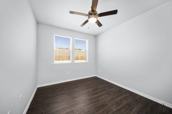an empty room with a ceiling fan and a window
