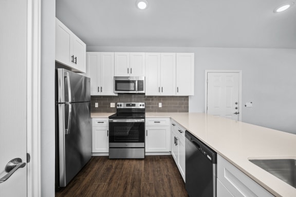 a kitchen with white cabinets and stainless steel appliances