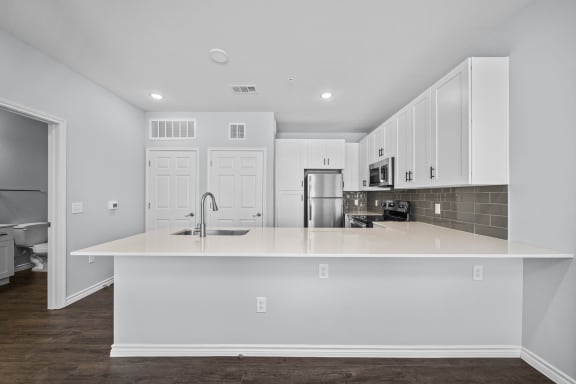 a white kitchen with a large counter top and a sink