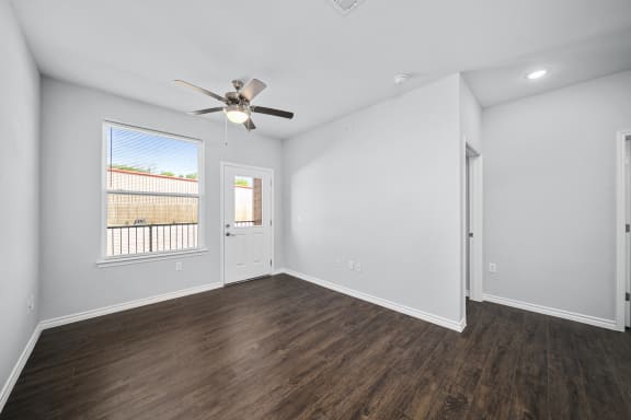 an empty living room with white walls and a ceiling fan