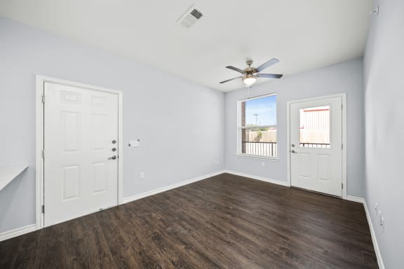 an empty living room with white walls and a ceiling fan