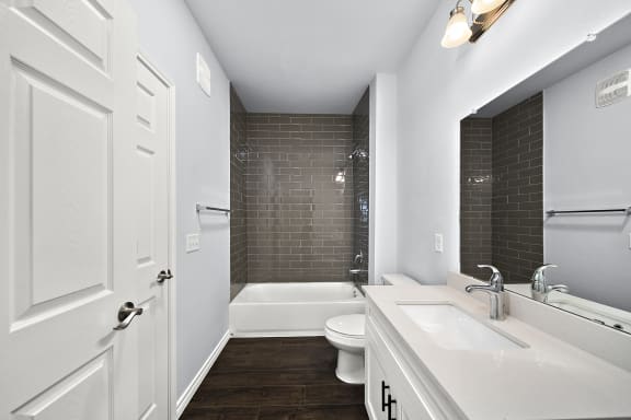 Modern bathroom with tiled tub and white vanity at The Aurea Apartments, Houston, Texas
