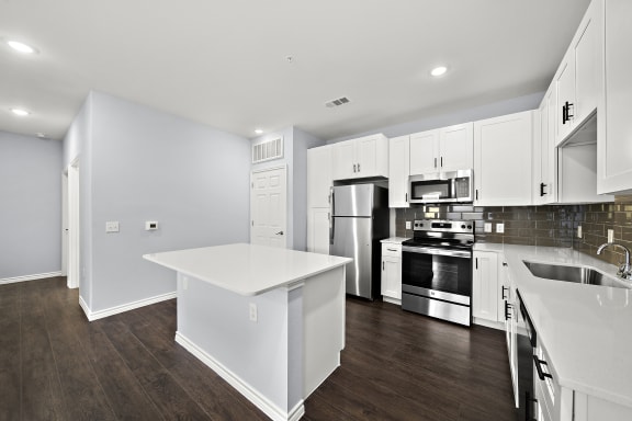 Open concept kitchen with white island and countertops at The Aurea Apartments, Houston