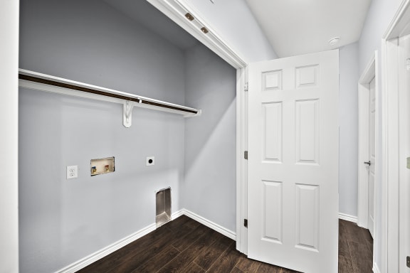 Laundry room with closet rod and dark flooring at The Aurea Apartments, Houston, TX 77093