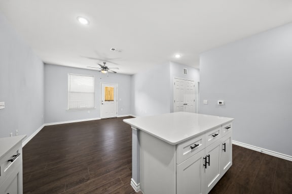 Open concept kitchen with white cabinetry and island at The Aurea Apartments, Houston, 77093