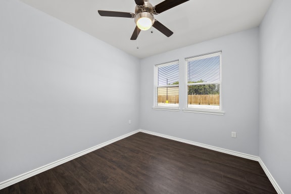 an empty room with a ceiling fan and a window