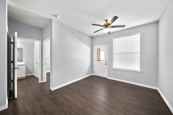 an empty living room with wood floors and a ceiling fan