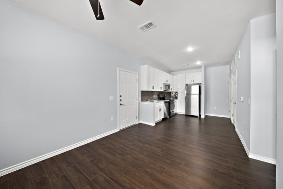 a kitchen and living room with white walls and wood flooring