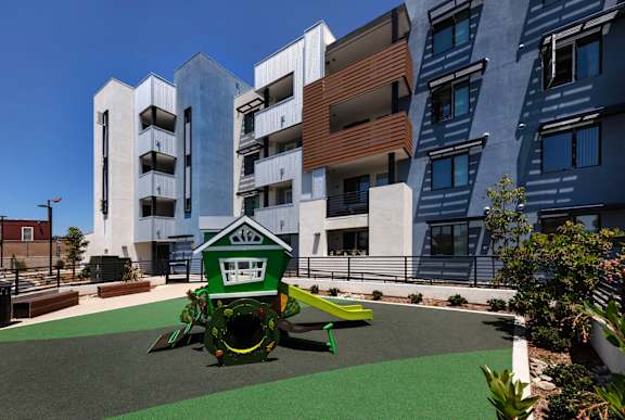 A playground with a green slide and a white building in the background.