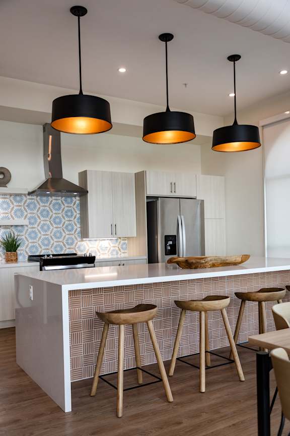 A kitchen with a white counter and wooden stools.