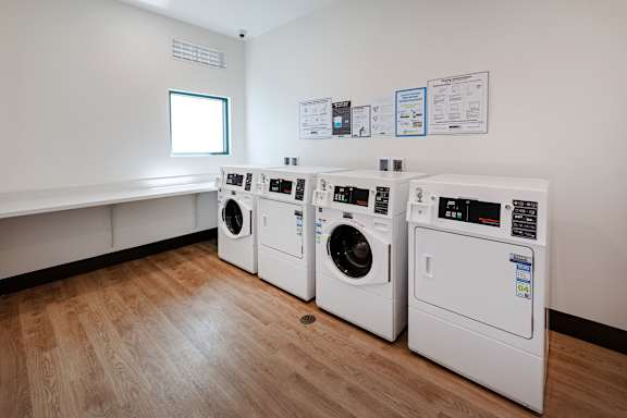 Three washing machines are lined up in a laundry room.