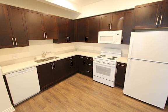 A kitchen with white appliances and brown cabinets.