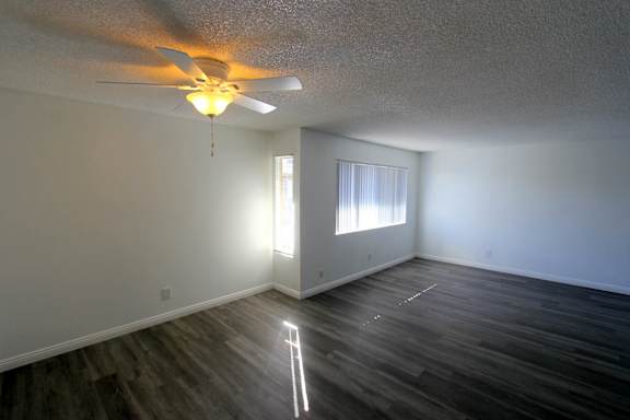 A room with a ceiling fan and a window with blinds.