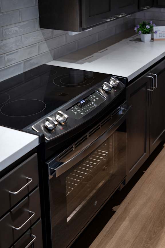 A modern kitchen with a black stove top oven and wooden cabinets.