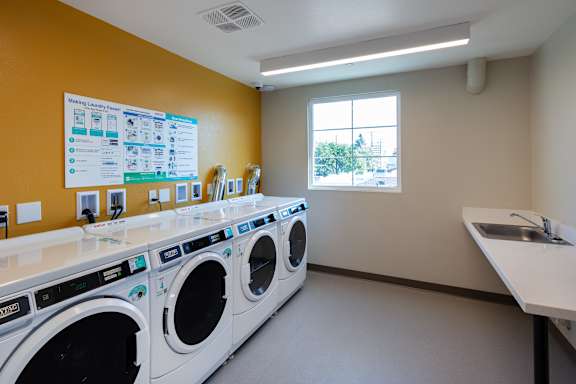 A laundromat with a row of washers and dryers.